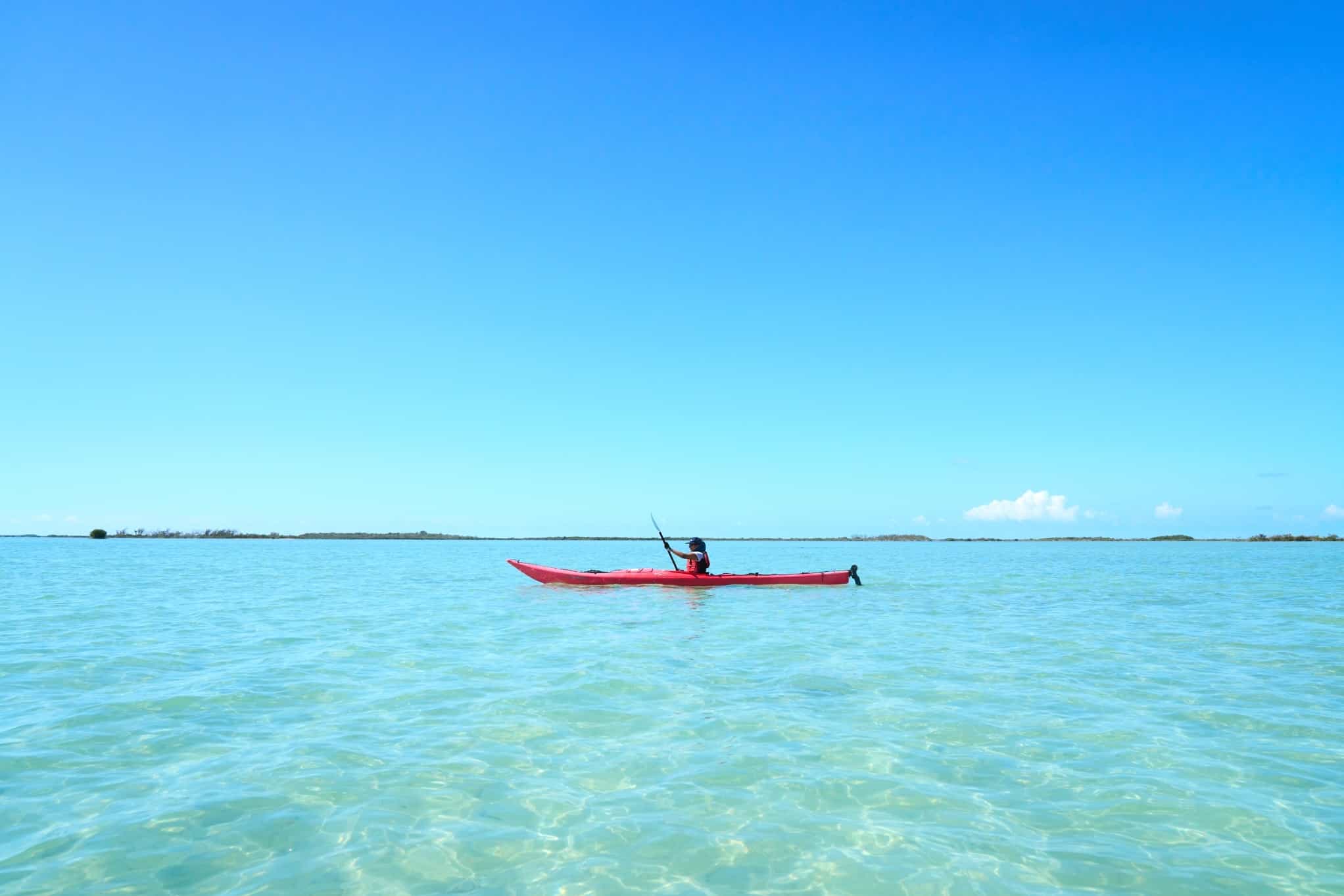 Person kayaking on bright clear water in Cuba.