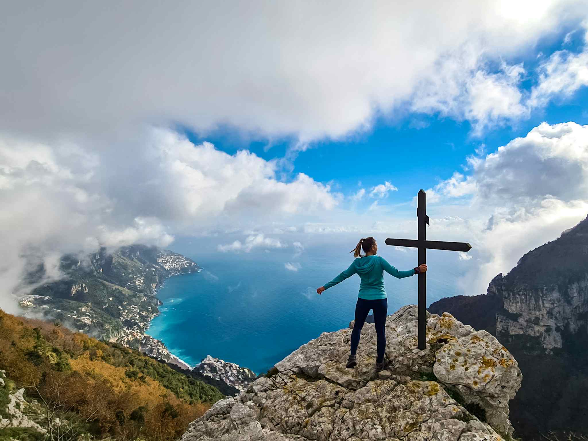 A hiker poses on the summit of Monte Molare, looking down at the Amalfi Coast. Photo: Adobe Stock.