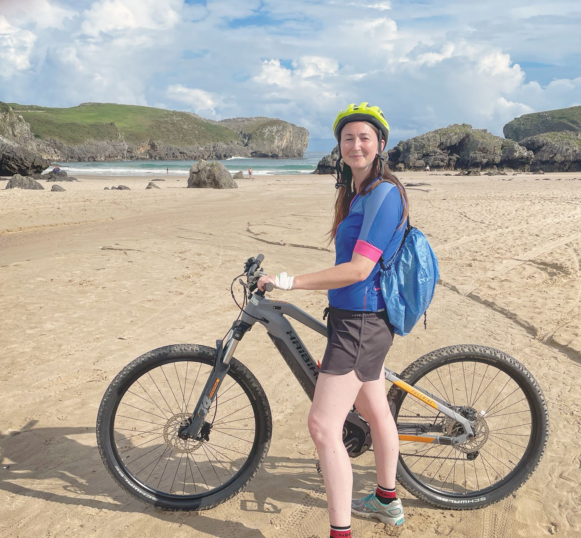 A girl stood by her e-bike on the beach in Asturias, Spain