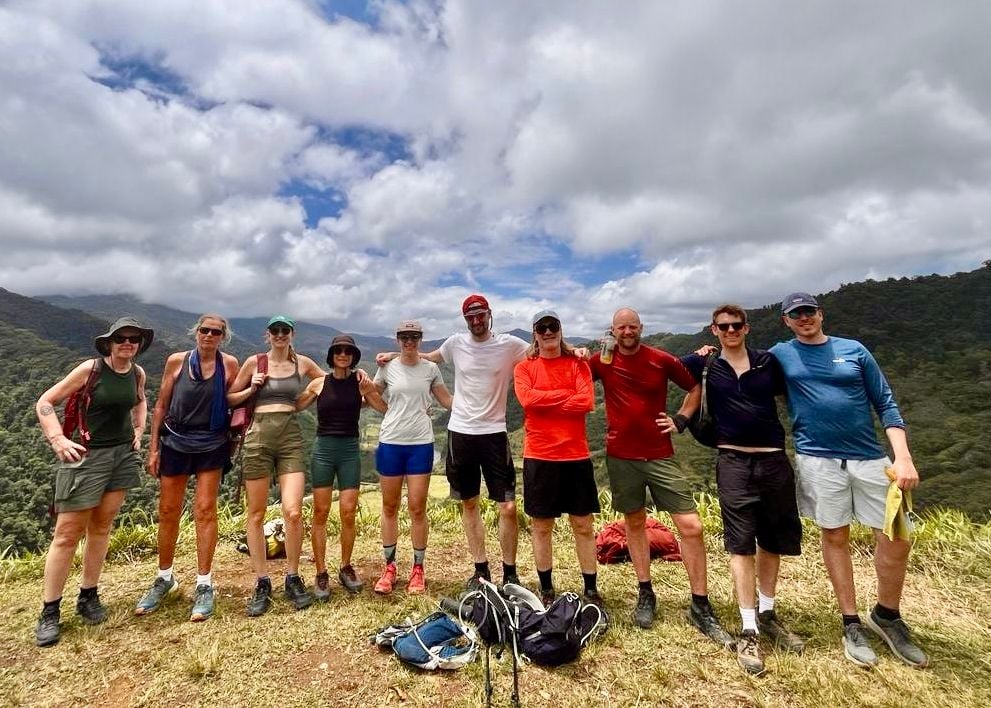 Group of 10 men and women stood in front of Costa Rican landscape