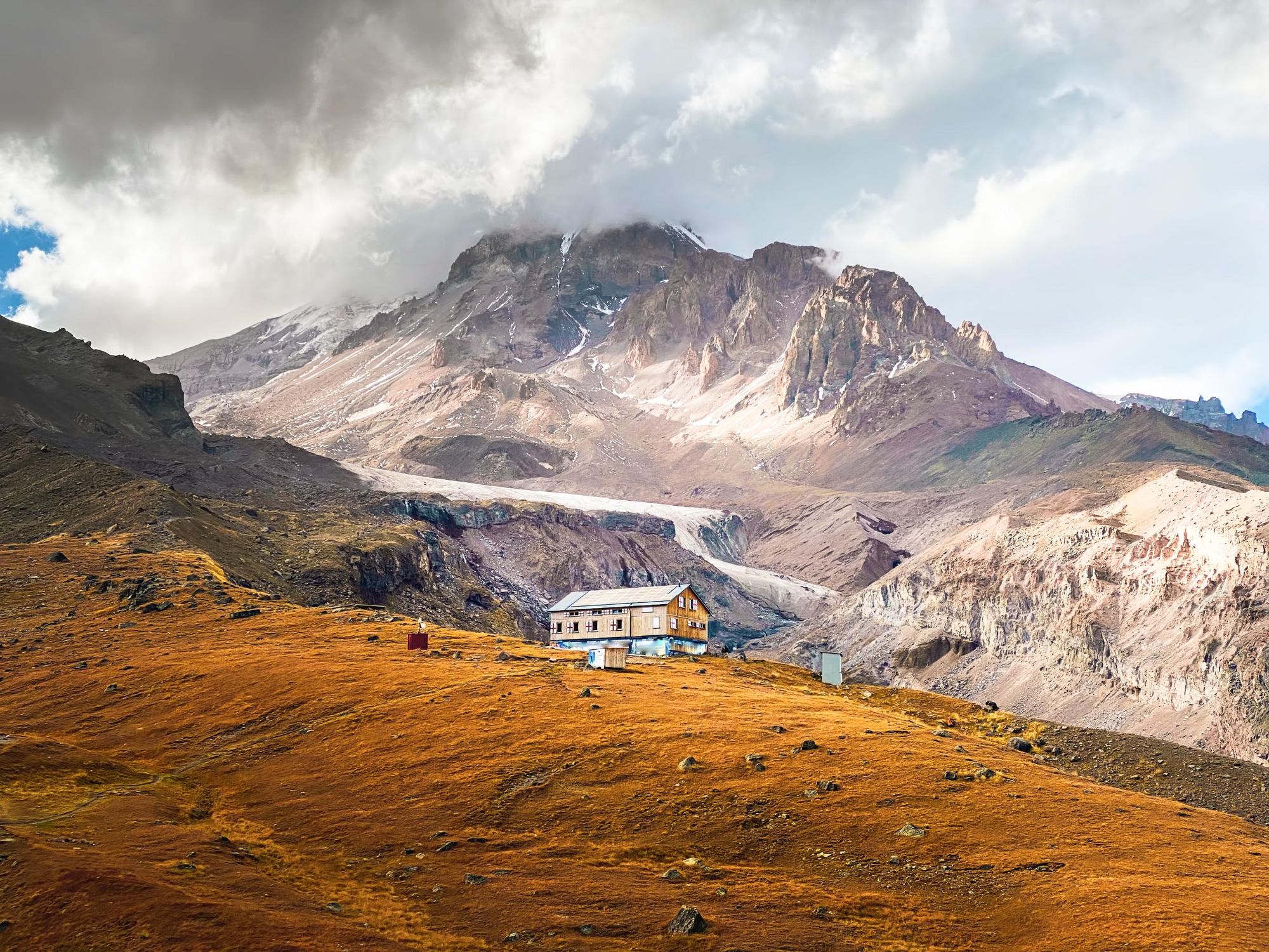 The Alti Hut with a view of Mount Kazbek in Caucasus, Georgia. The slopes are barren and stony below the snow-capped peak and the Gergeti Glacier. Photo: Getty