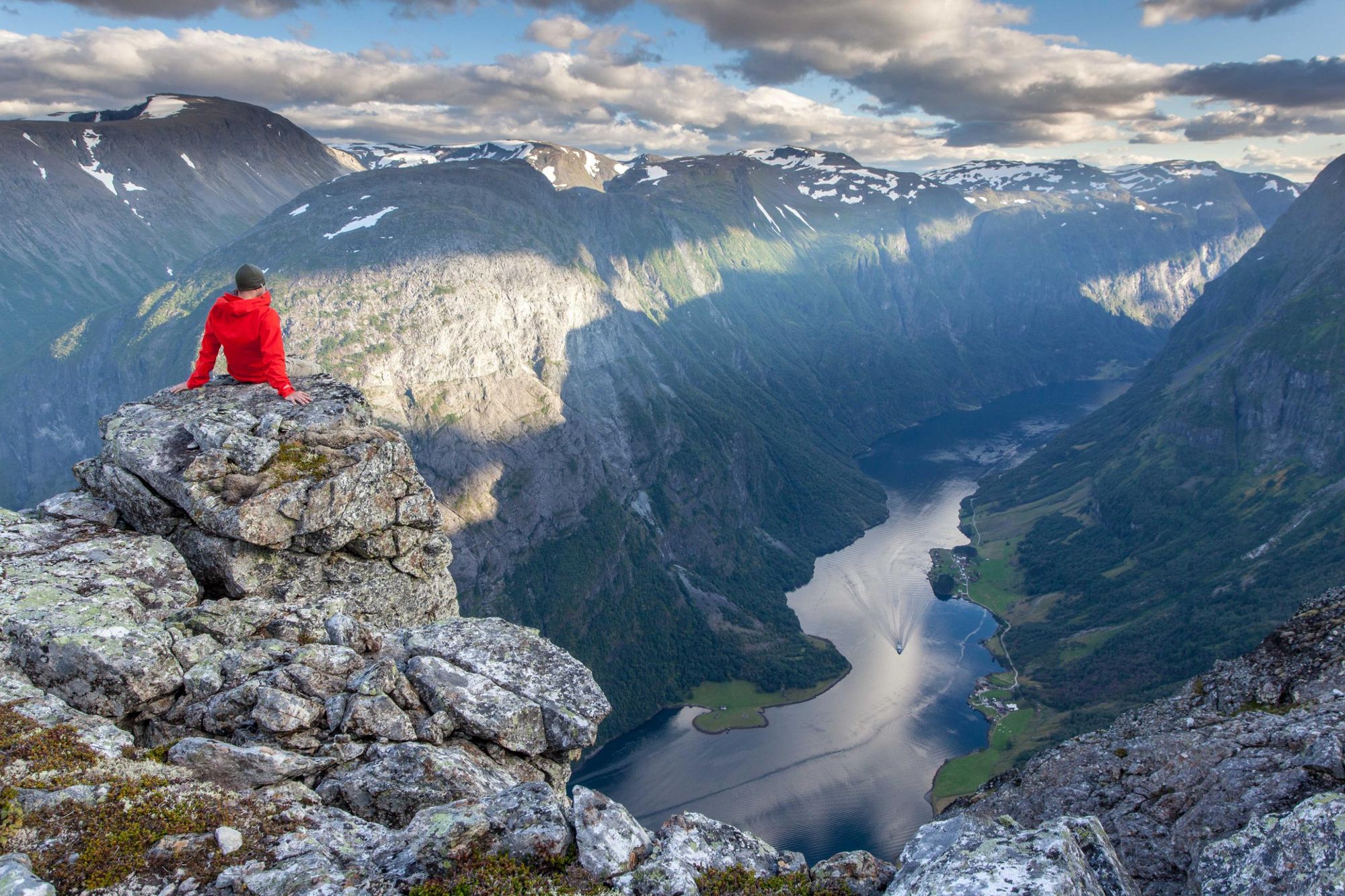 A man rests above the Naeroyfjord and enjoys the view from Breiskrednosi, a hiking point along the route. Photo: Getty