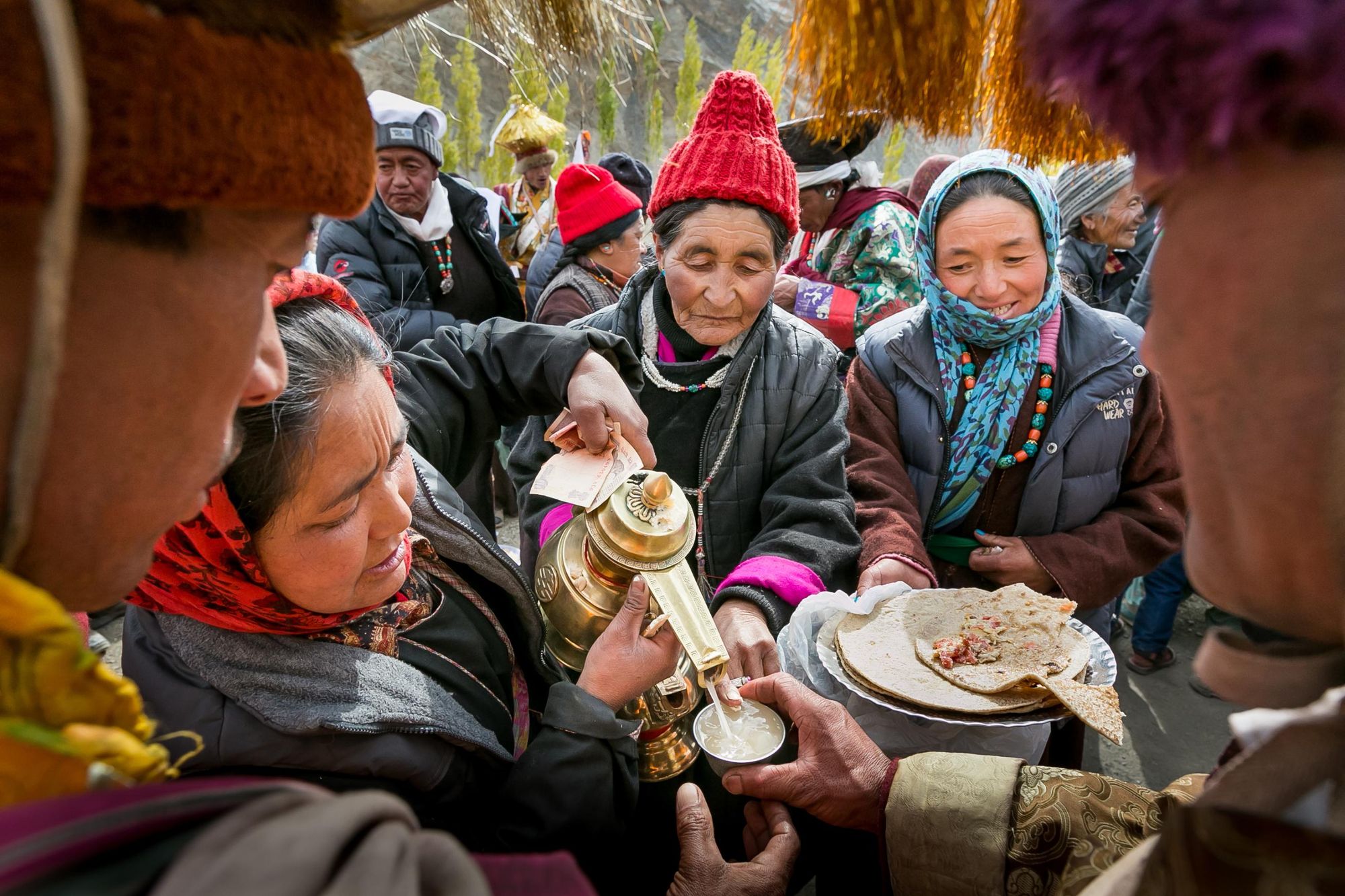 Women serve chhang (barley alcohol) and food at a Ladakhi wedding. Photo: Getty.