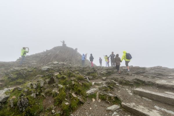pieni ryhmä vaeltajia sumussa aivan Snowdon-vuoren huipulla Walesissa